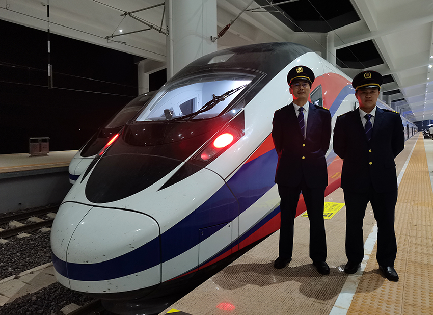 劉銀能（右一）與中國(guó)師父鄔俊鴻在動(dòng)車(chē)組前合影。受訪者供圖